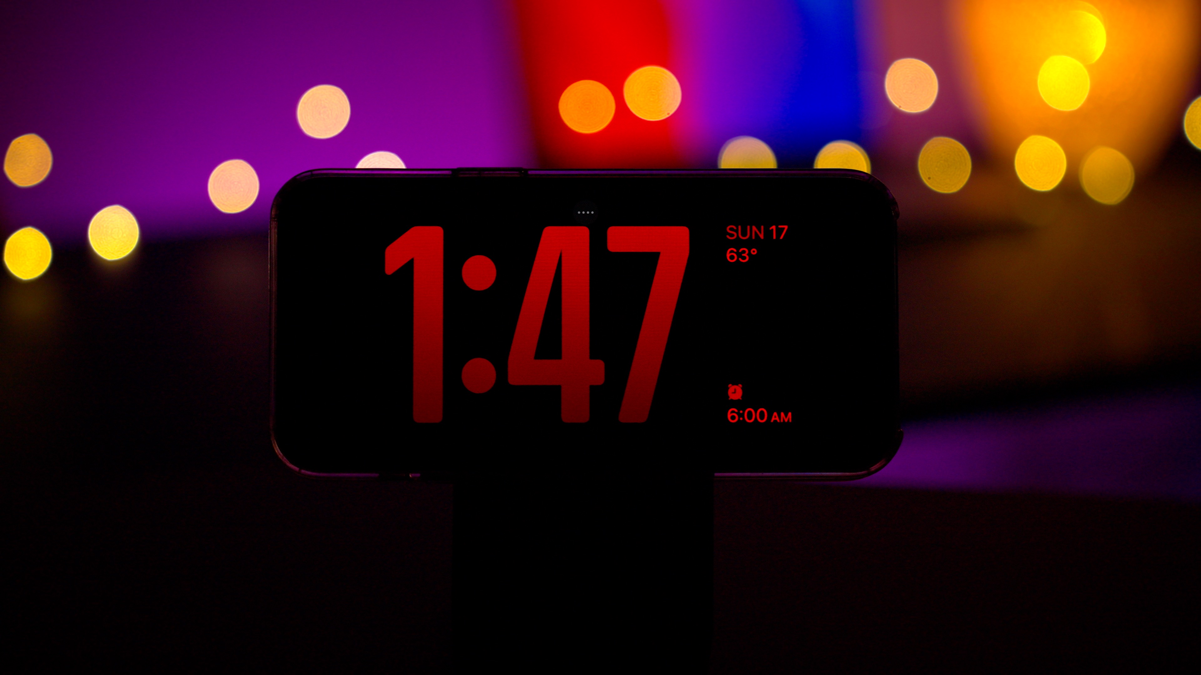Режим ожидания в iOS 17 показывает часы в ночном режиме.