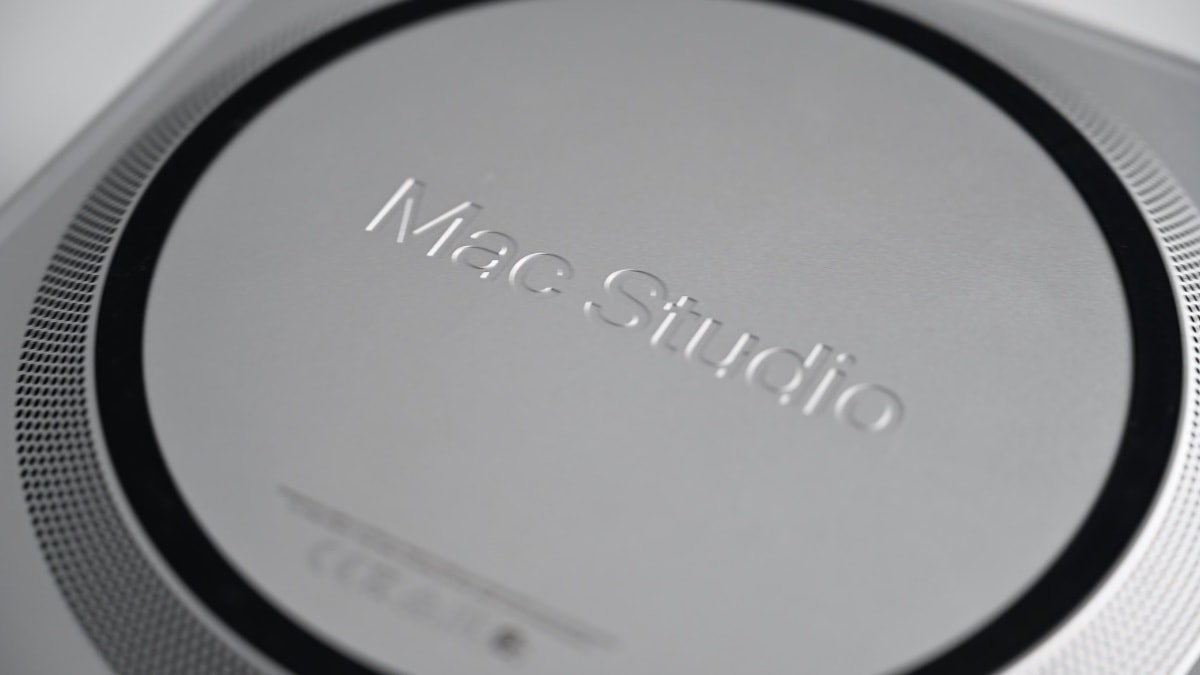 Крупный план верхней части компьютера Mac Studio с тисненым логотипом, демонстрирующим круглый дизайн и текстуру вентиляционной решетки.