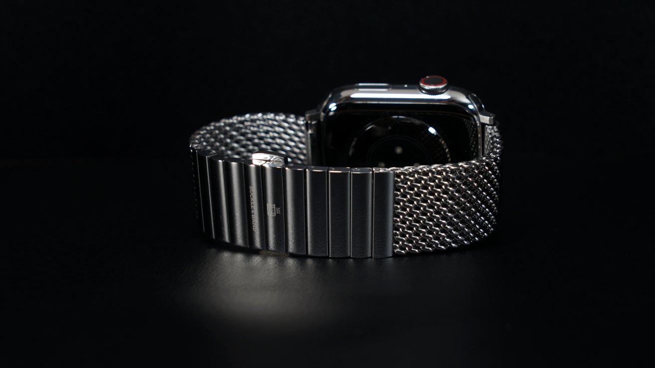 Apple Watch из нержавеющей стали с сетчатым браслетом элегантно стоят на темном столе.