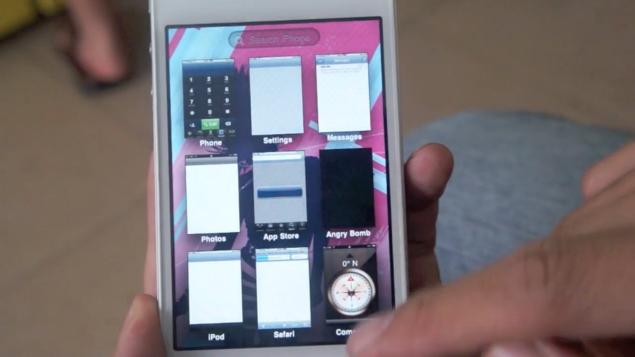 Рука держит смартфон с различными приложениями на розовом фоне.