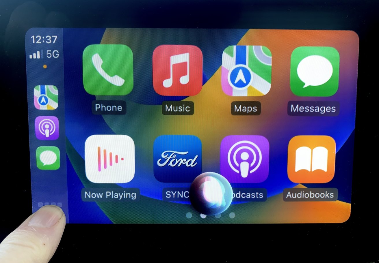 В меню CarPlay отображаются красочные значки приложений, включая «Телефон», «Музыка», «Карты» и «Сообщения», с отражением на экране.