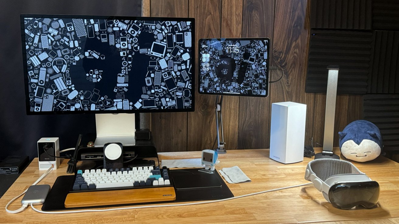 Рабочий стол с большим монитором и iPad с логотипом AppleInsider.  На столе лежит Apple Vision Pro.
