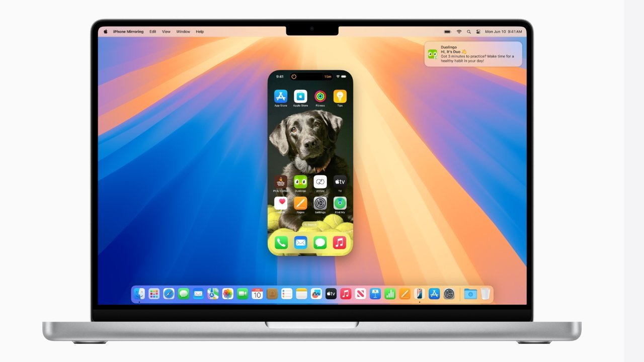 Экран MacBook, на котором отображается экран iPhone с фотографией собаки и приложениями.  Уведомление Duolingo появится в правом верхнем углу.